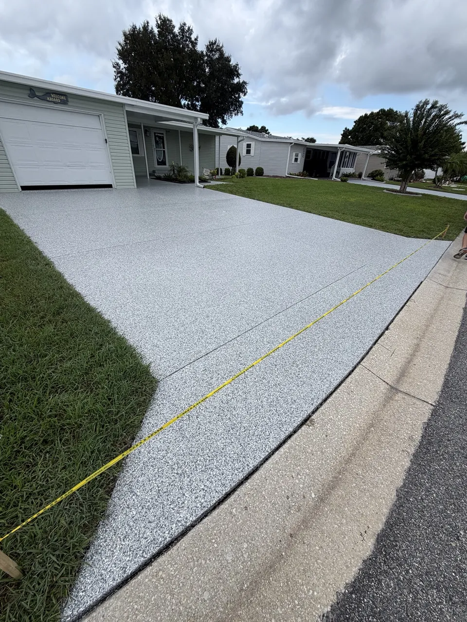 Finished light gray driveway coating extending to the street