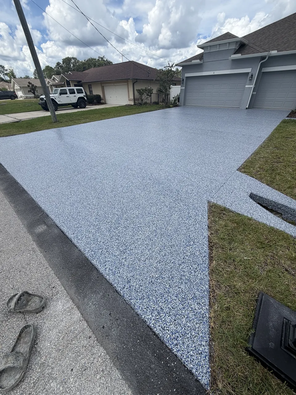 Gray decorative driveway coating in front of a two car garage