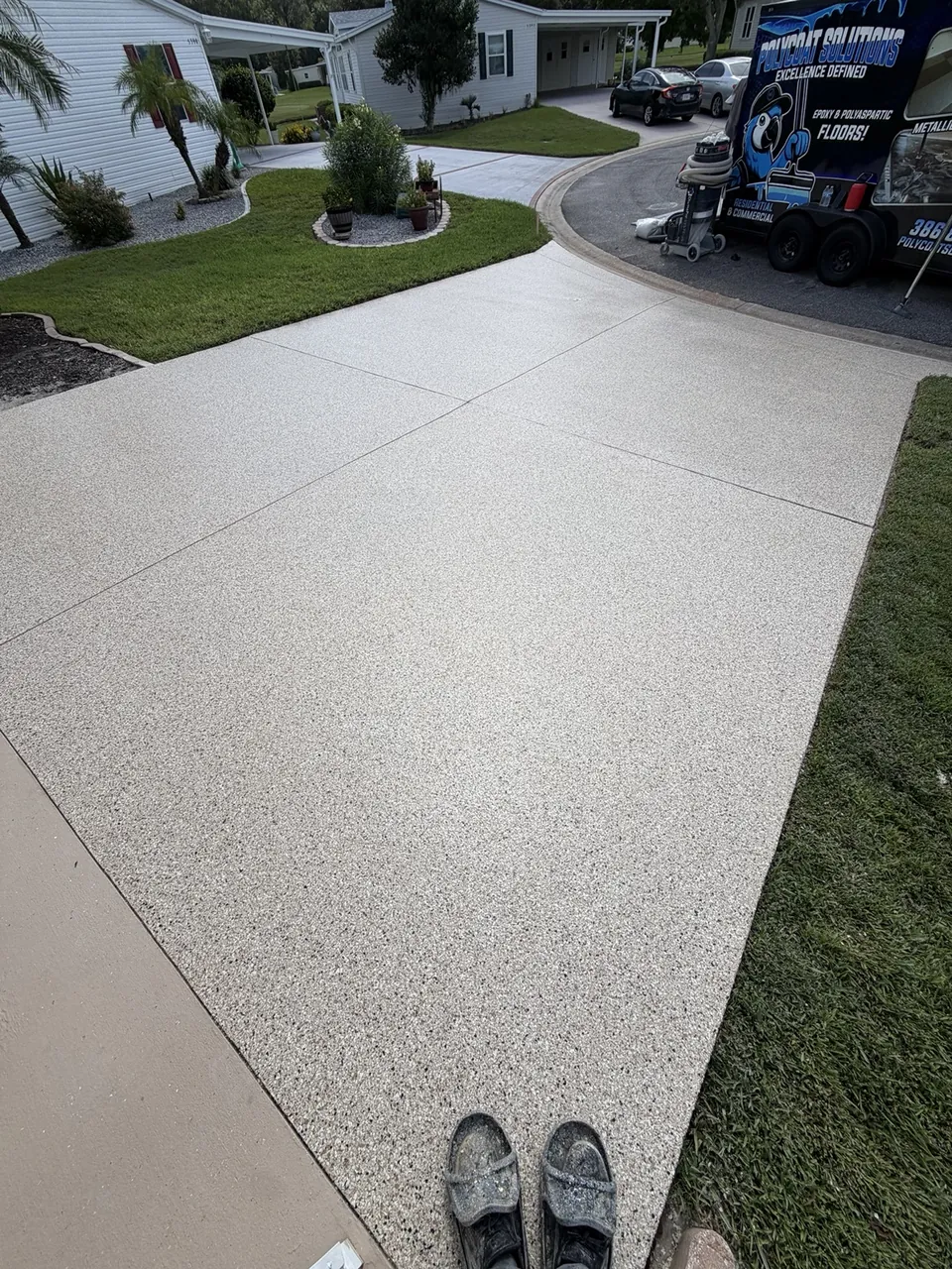 Light decorative driveway coating beside a landscaped front yard