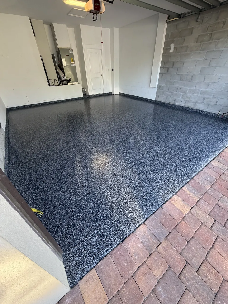 Dark gray flake garage floor bordered by a paver driveway