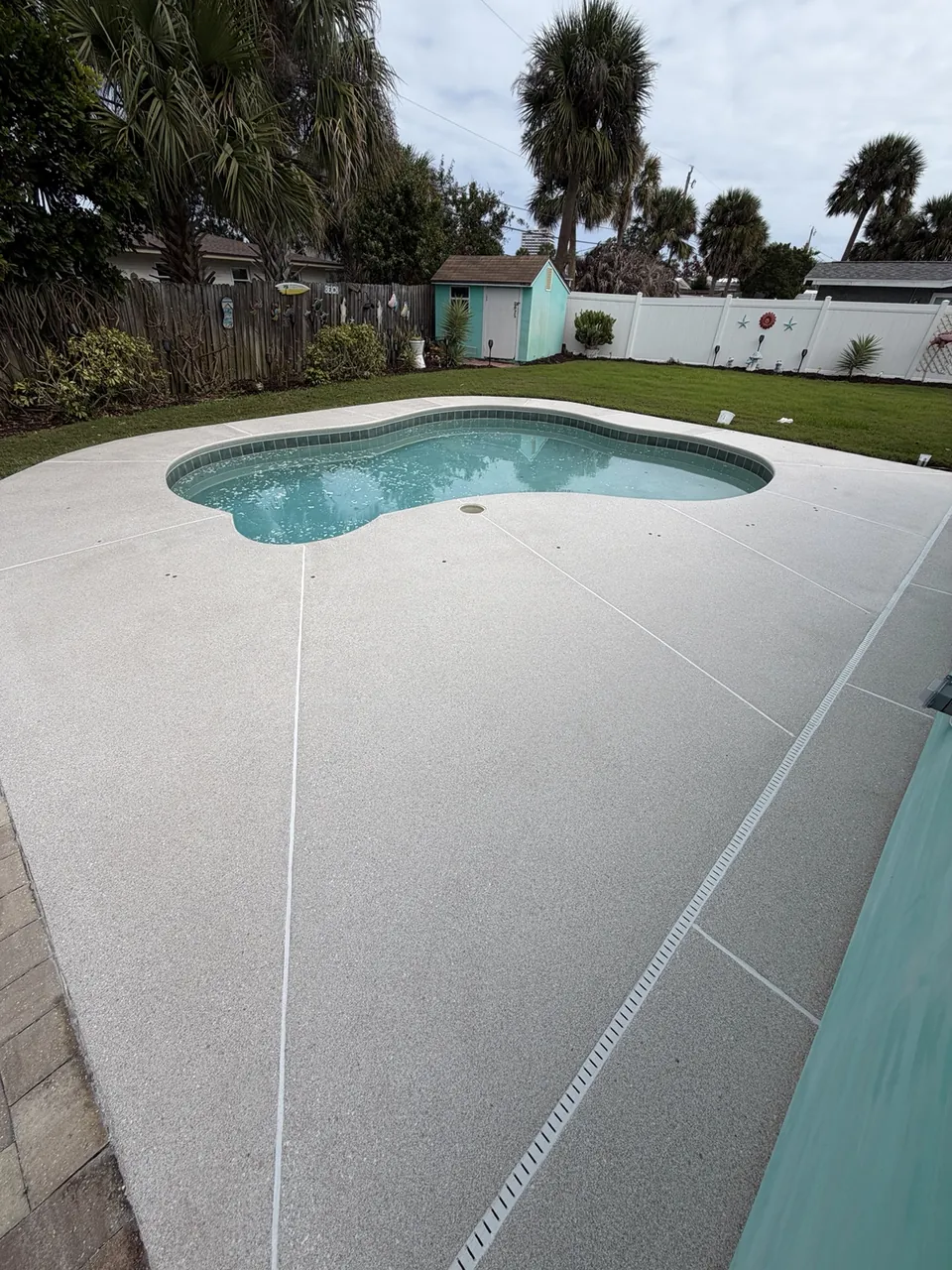 Light coated pool deck around a curved backyard pool