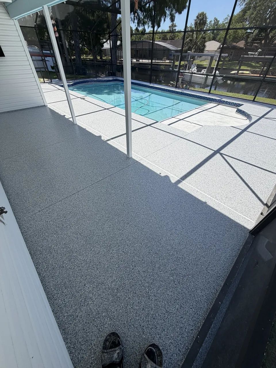 Two tone gray pool deck coating in a screened enclosure