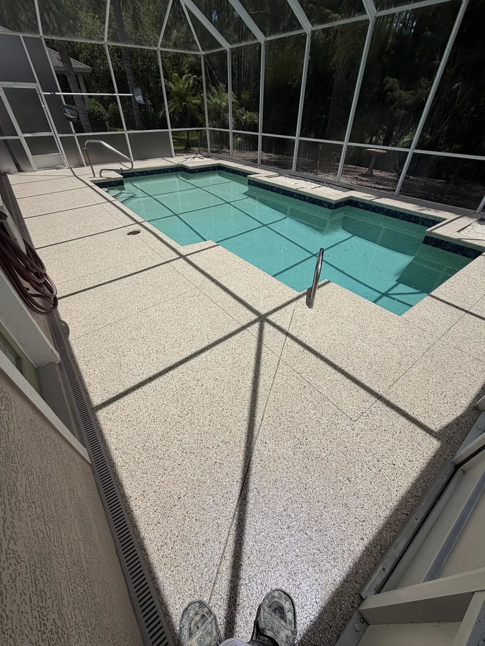 Tan coated pool deck inside a screened enclosure
