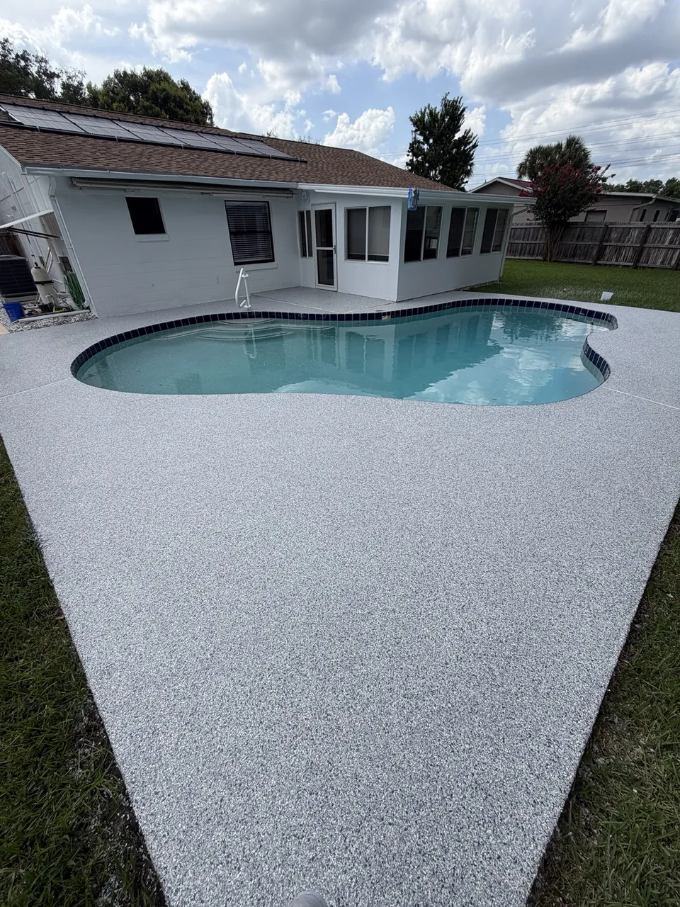 Light gray decorative coating surrounding a backyard pool