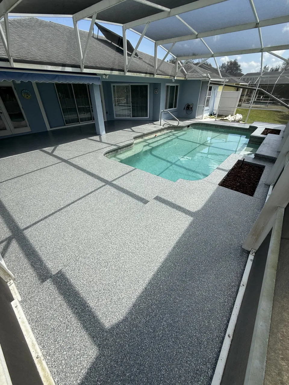 Gray coated pool deck and patio within a screen enclosure