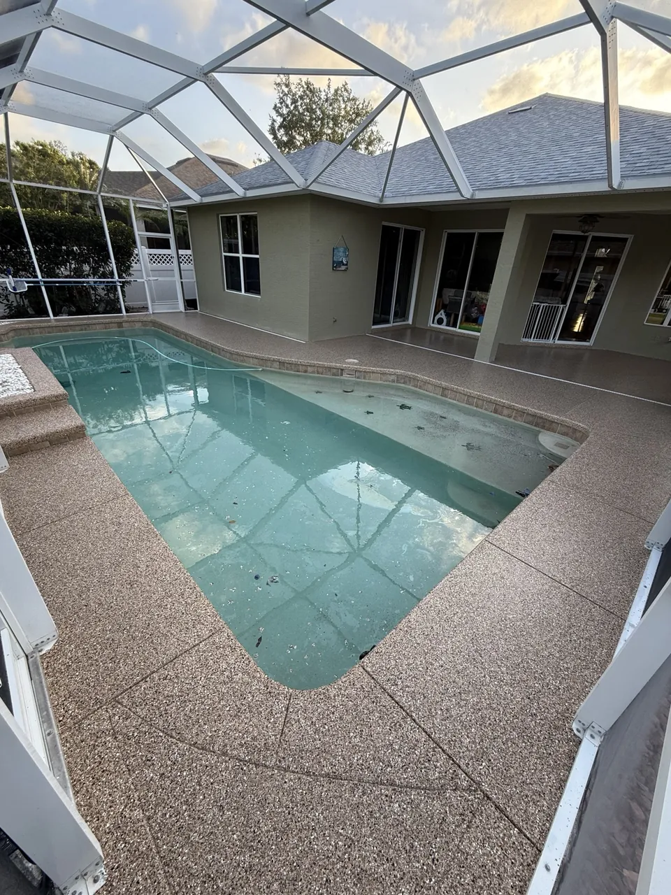 Warm tan coated pool deck within a screened patio
